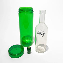 Gravity bong parts with clear glass bottle, green chamber, lid, and bowl on white background