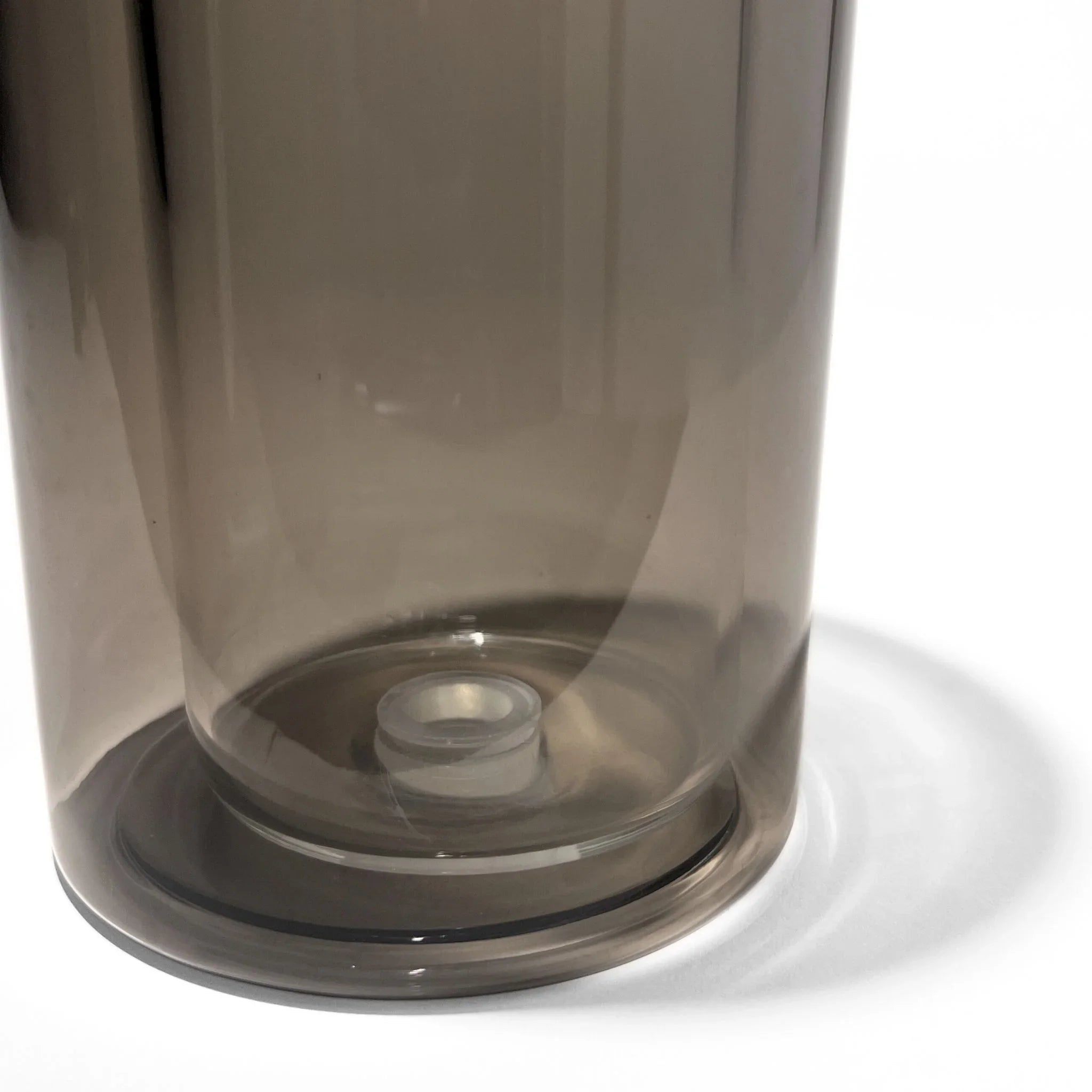 Close-up of a modern glass gravity bong base with smoke chamber on white background