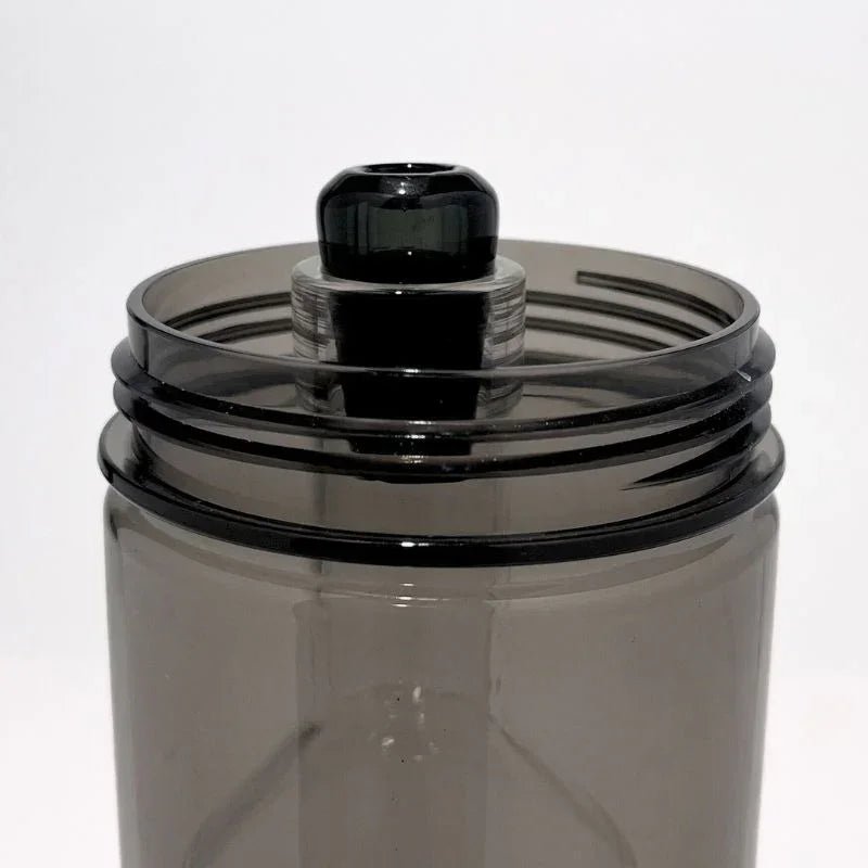 Close-up of a modern glass gravity bong top with clear and dark components against a white background